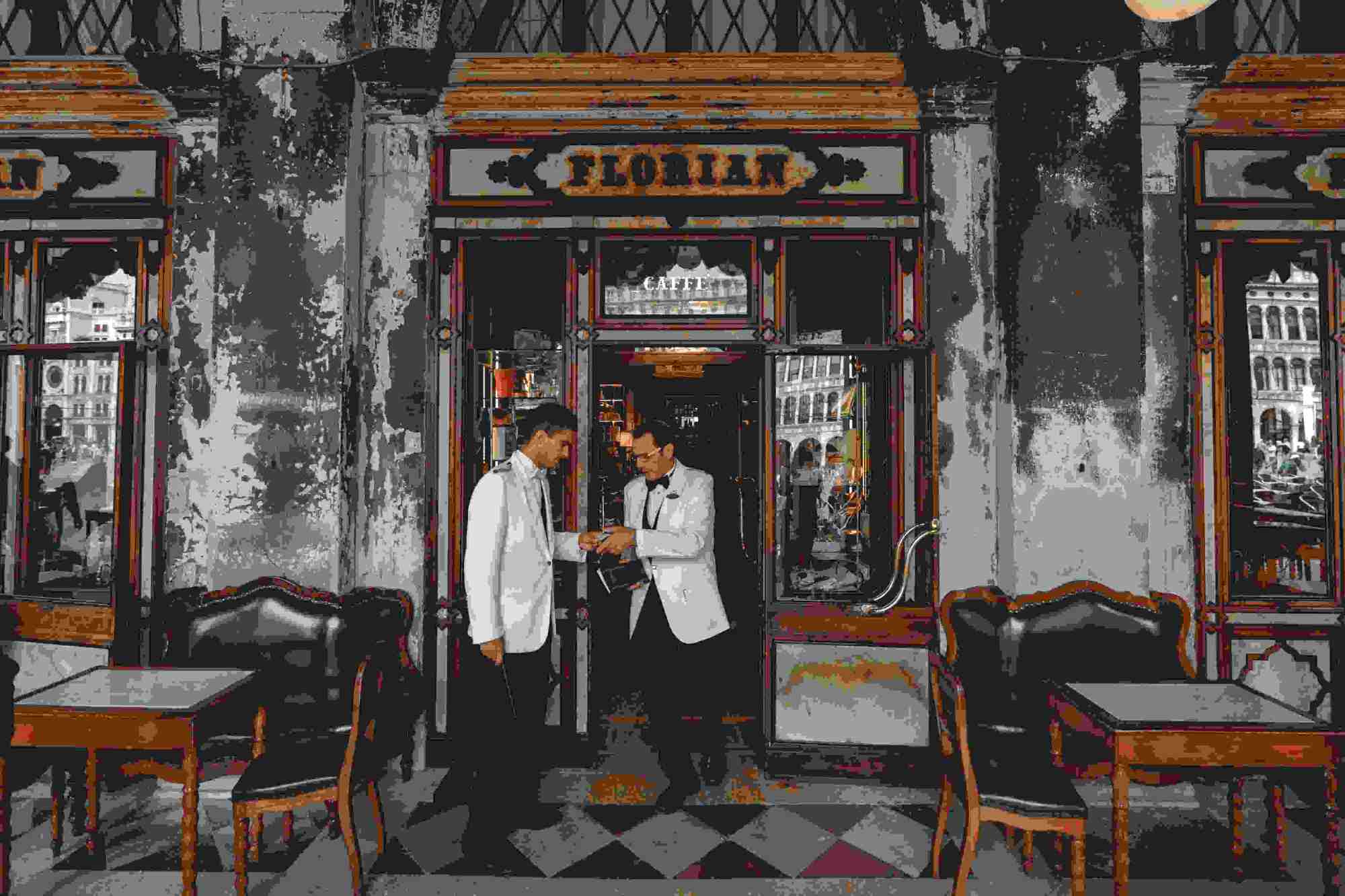 Das Bild zeigt zwei Kellner vor einem Restauranteingang.