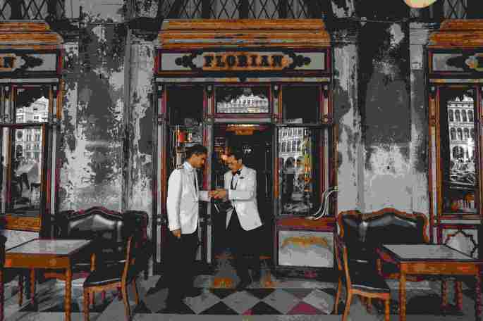 Das Bild zeigt zwei Kellner vor einem Restauranteingang.