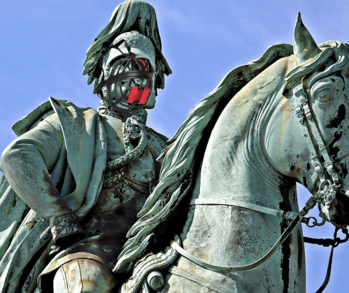 Das Bild zeigt ein Reiterdenkmal. Über das Gesicht ist ein Maulkorb gezogen.