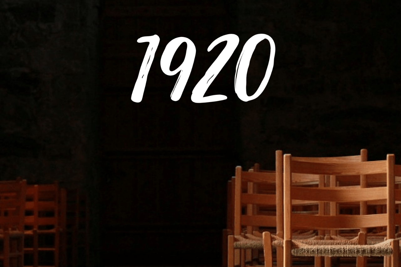 Das Foto zeigt Holzstühle vor einem schwarzen Hintergrund; zu sehen ist die Jahreszahl 1920.
