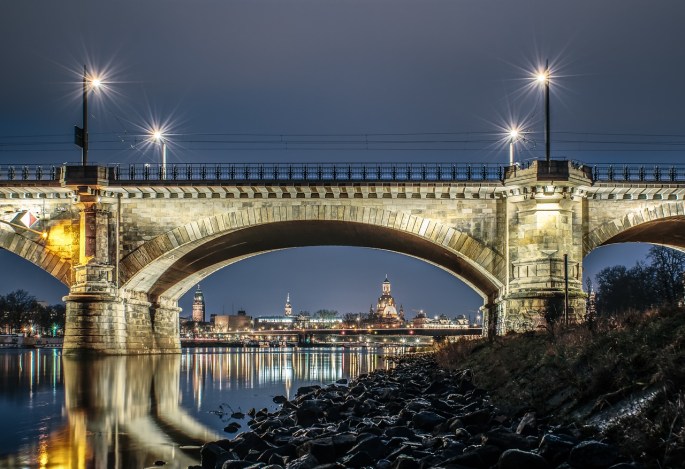 Das Bild zeigt eine beleuchtete Brücke in Dresden bei Nacht.