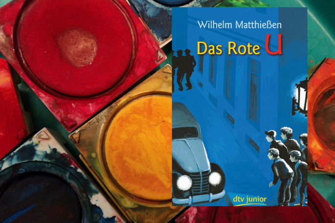Das Bild zeigt Wassermalfarben eines Farbkastens; in der rechten Hälfte ist das Buchcover des Kinderromans "Das rote U" zu sehen.